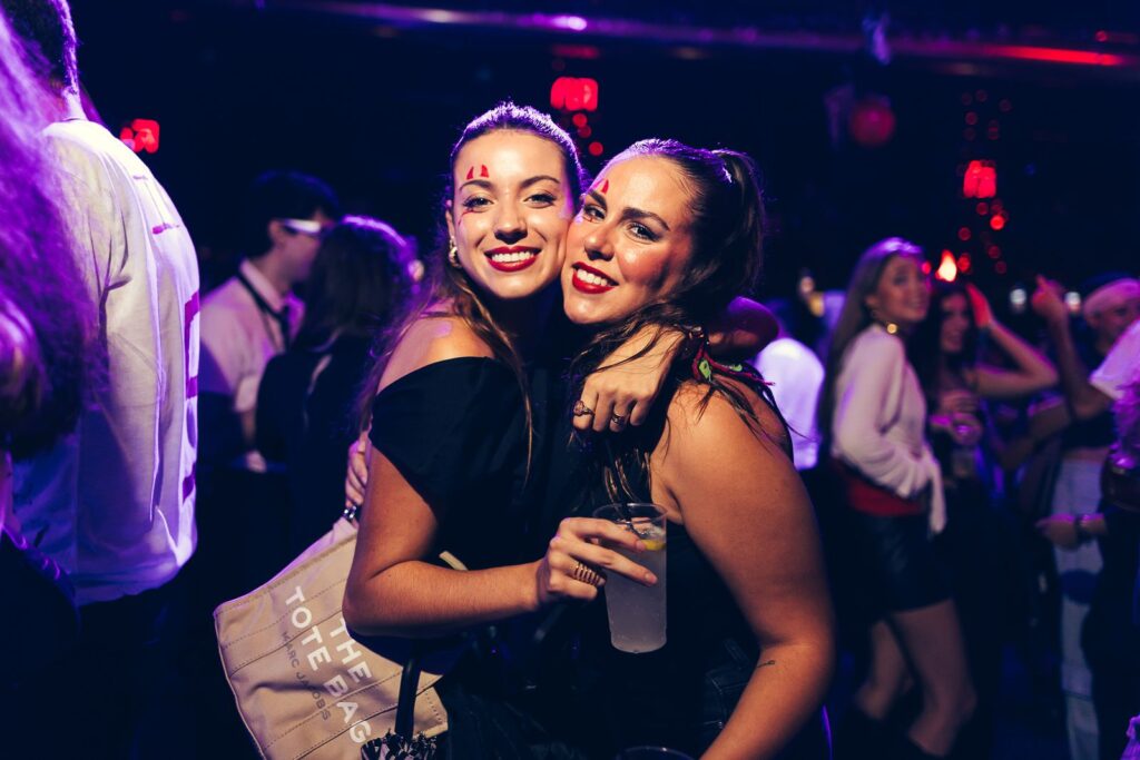 Two friends with Halloween make-up hugging on the dance floor in Florence