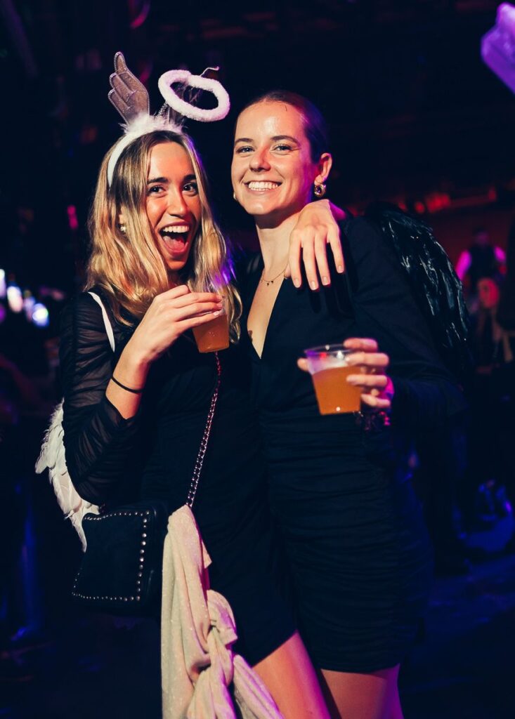 Two friends at a Halloween party in Florence, one dressed as an angel with a halo
